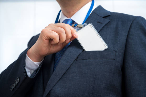 Businessman in suit wearing a blank ID tag or name card on a lanyard at an exhibition or conference